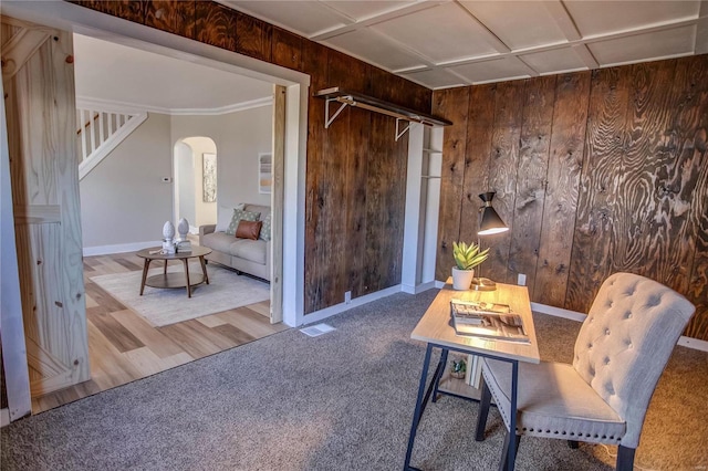 carpeted office space featuring arched walkways, wooden walls, visible vents, and baseboards