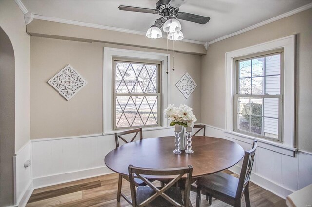 dining area featuring wainscoting, plenty of natural light, wood finished floors, and crown molding