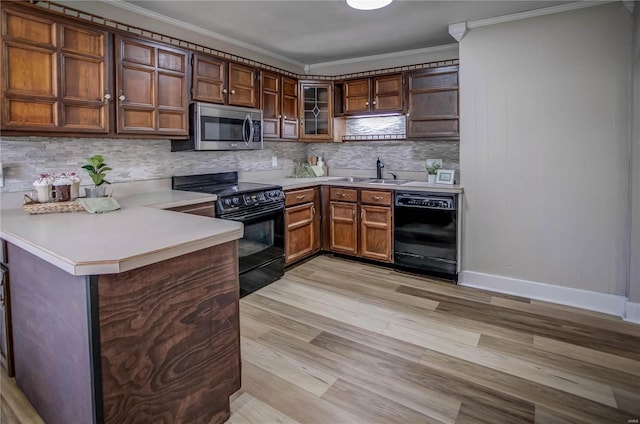 kitchen with a peninsula, ornamental molding, decorative backsplash, black appliances, and light countertops