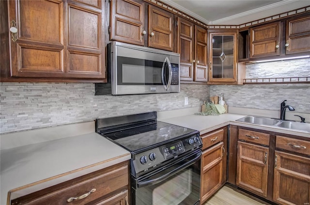 kitchen featuring tasteful backsplash, stainless steel microwave, light countertops, electric range, and a sink