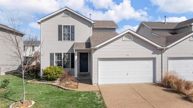 traditional-style house featuring a front yard, an attached garage, driveway, and a shingled roof
