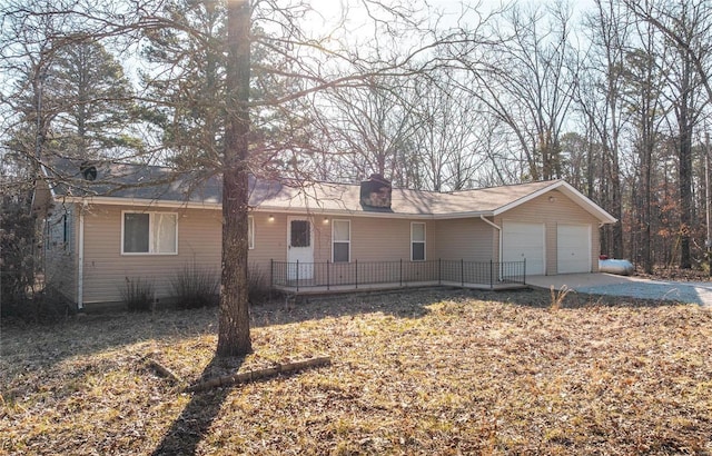 rear view of house featuring an attached garage, a chimney, and driveway