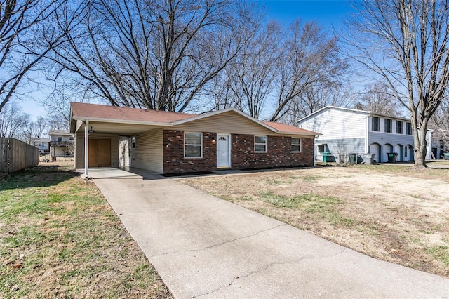 view of front of property featuring brick siding, an attached carport, fence, concrete driveway, and a front yard