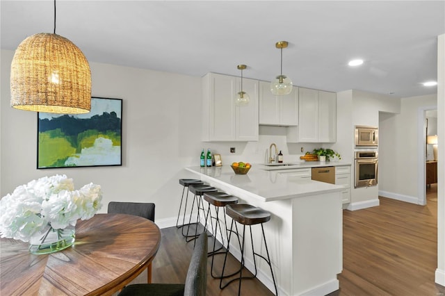 kitchen featuring a sink, white cabinetry, stainless steel appliances, light countertops, and dark wood-style flooring