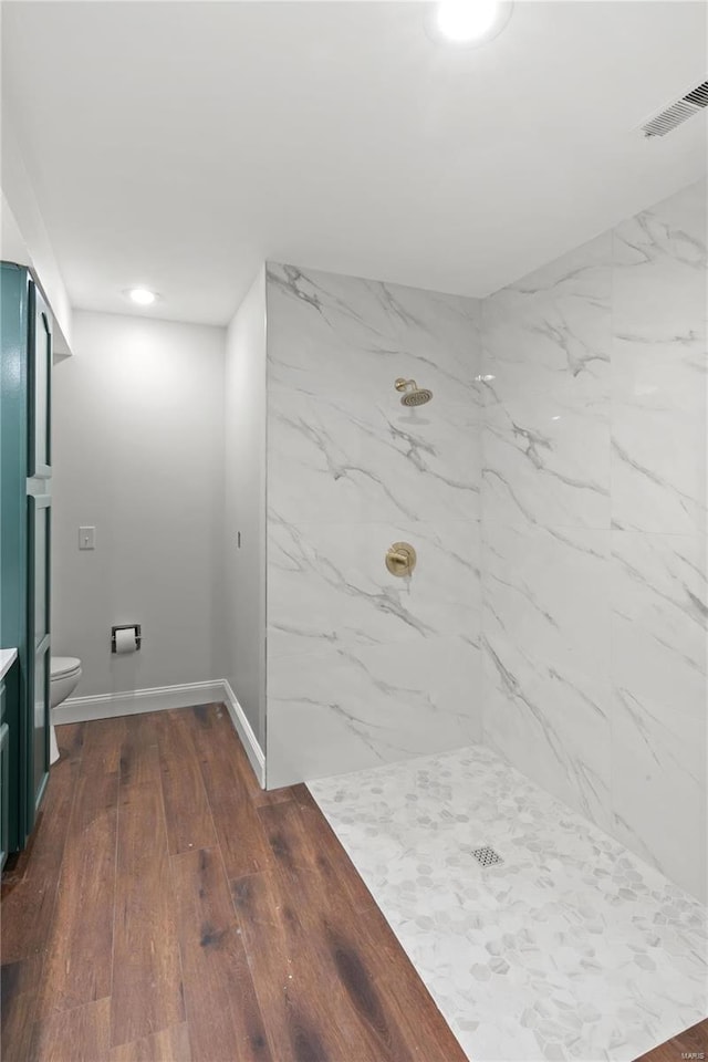 bathroom with visible vents, toilet, a marble finish shower, wood-type flooring, and baseboards