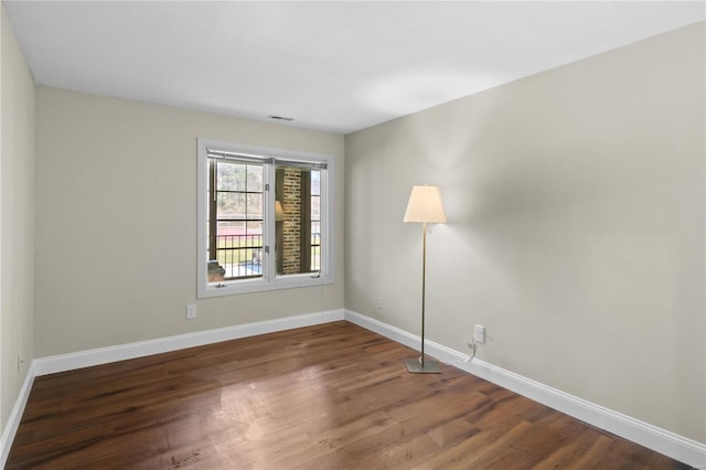 empty room featuring visible vents, baseboards, and wood finished floors