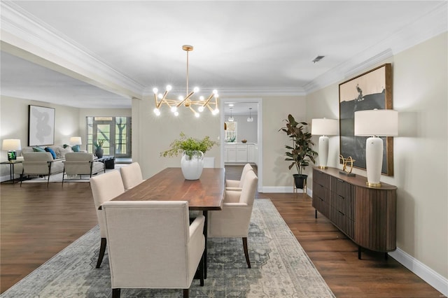 dining area featuring visible vents, dark wood-type flooring, a notable chandelier, crown molding, and baseboards