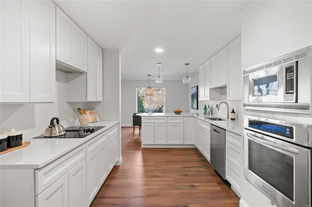 kitchen featuring a sink, dark wood finished floors, appliances with stainless steel finishes, a peninsula, and white cabinets