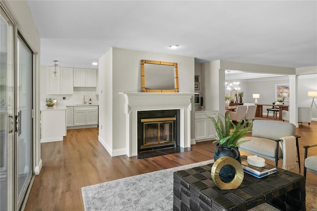 living room with a fireplace with flush hearth, wood finished floors, and baseboards