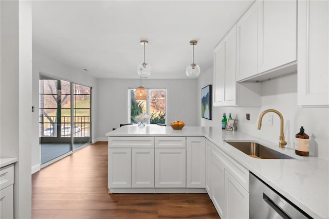 kitchen featuring a sink, light countertops, a peninsula, dark wood-style floors, and stainless steel dishwasher