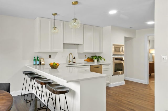 kitchen with a sink, a kitchen bar, appliances with stainless steel finishes, and white cabinetry