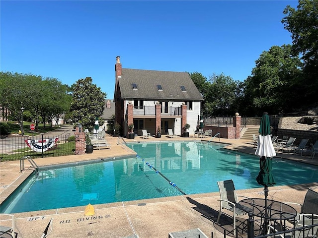 community pool with a patio area and fence