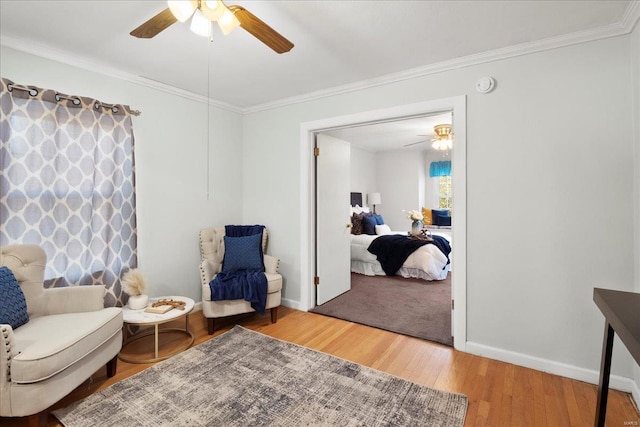 living area with ceiling fan, wood finished floors, baseboards, and ornamental molding