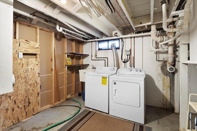 clothes washing area with a sink, laundry area, and washer and clothes dryer