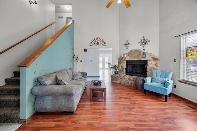 living room featuring stairs, a stone fireplace, wood finished floors, and a healthy amount of sunlight