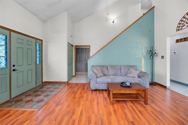 interior space featuring visible vents, baseboards, wood finished floors, and a towering ceiling