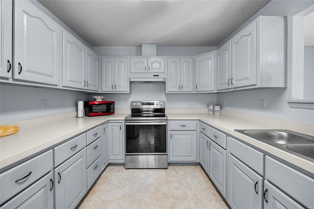 kitchen featuring under cabinet range hood, a textured ceiling, stainless steel range with electric stovetop, and light countertops