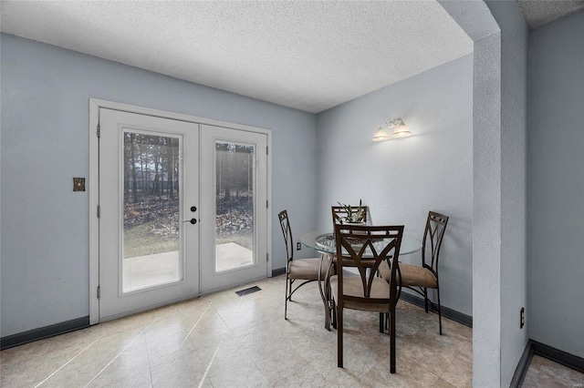 dining room featuring french doors, baseboards, a textured ceiling, and visible vents