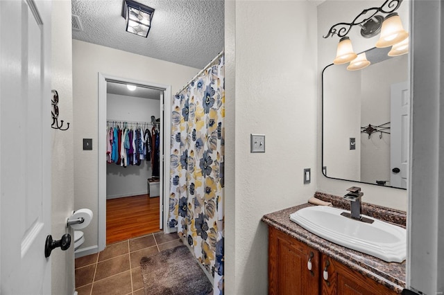 bathroom with a walk in closet, curtained shower, a textured ceiling, tile patterned flooring, and vanity