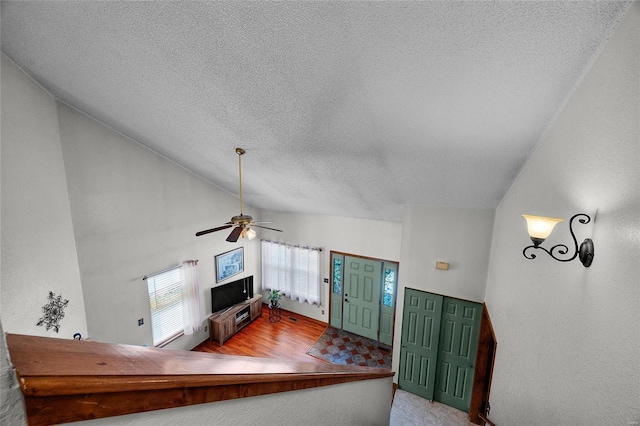 foyer with high vaulted ceiling, a textured ceiling, wood finished floors, and a ceiling fan