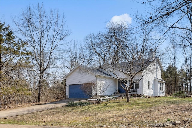 view of front of property with a garage, driveway, a chimney, and a front lawn