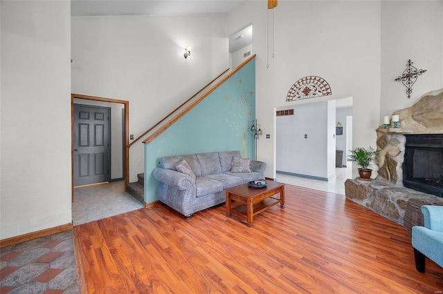living room with stairway, a towering ceiling, and wood finished floors