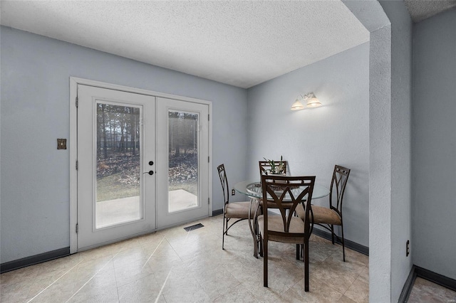 dining area with a textured ceiling, french doors, baseboards, and visible vents