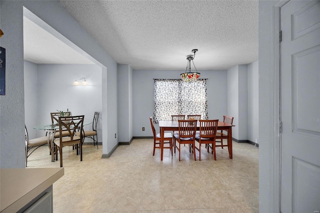 dining space with a textured ceiling, baseboards, and light floors