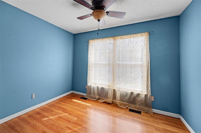 spare room with visible vents, baseboards, and wood finished floors