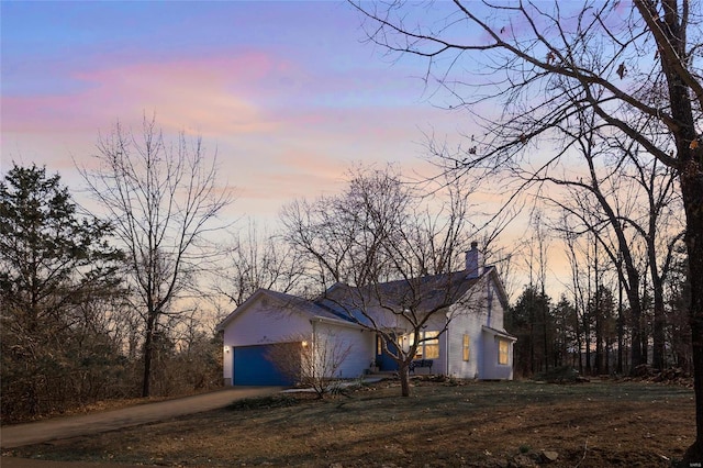 view of property exterior featuring a lawn, a garage, driveway, and a chimney