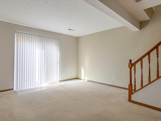 unfurnished living room featuring visible vents, a textured ceiling, carpet, baseboards, and stairs