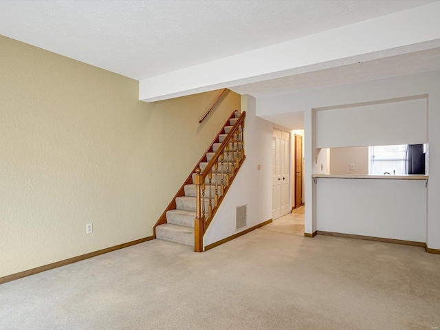 below grade area featuring fridge, stairway, light colored carpet, and baseboards