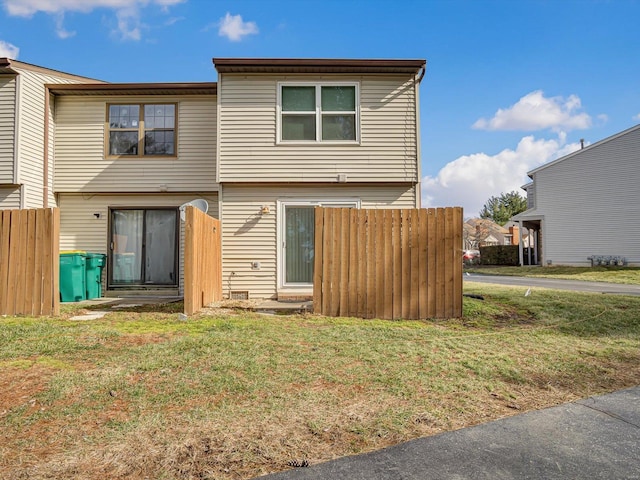 rear view of property featuring a yard and fence