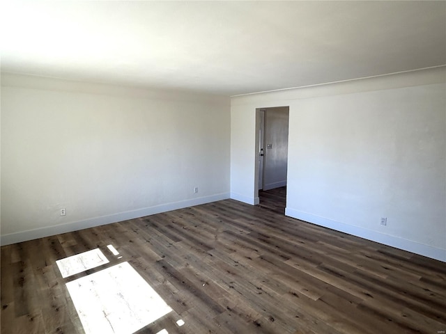 spare room with baseboards and dark wood-style floors