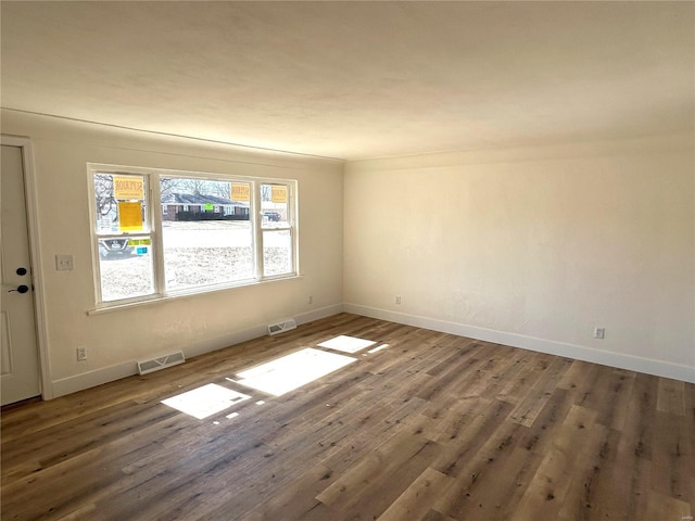 empty room featuring visible vents, baseboards, and wood finished floors