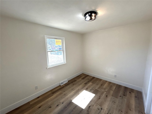 empty room featuring visible vents, baseboards, and wood finished floors