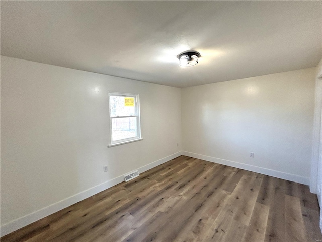 spare room with visible vents, baseboards, and wood finished floors