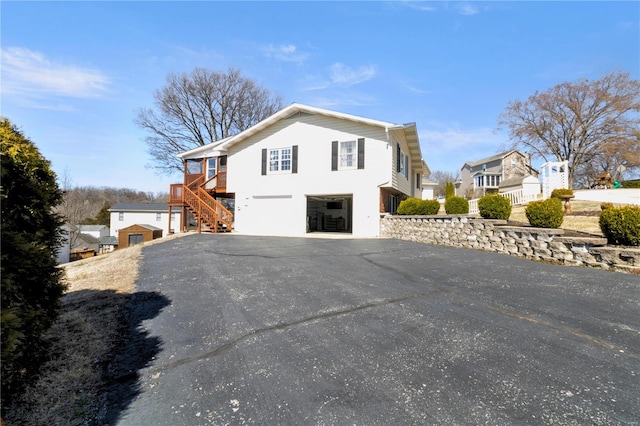 view of side of home featuring aphalt driveway, stairway, and an attached garage