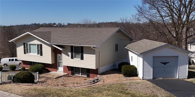 raised ranch with aphalt driveway, roof with shingles, an attached garage, and fence