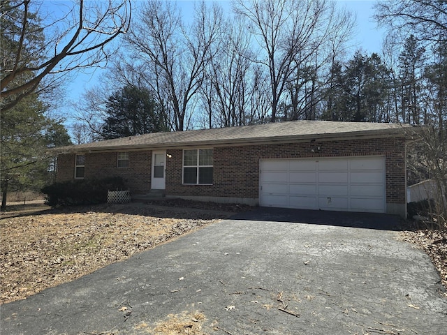 single story home featuring aphalt driveway, brick siding, and a garage