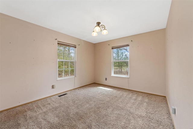 unfurnished room with a chandelier, visible vents, carpet flooring, and baseboards