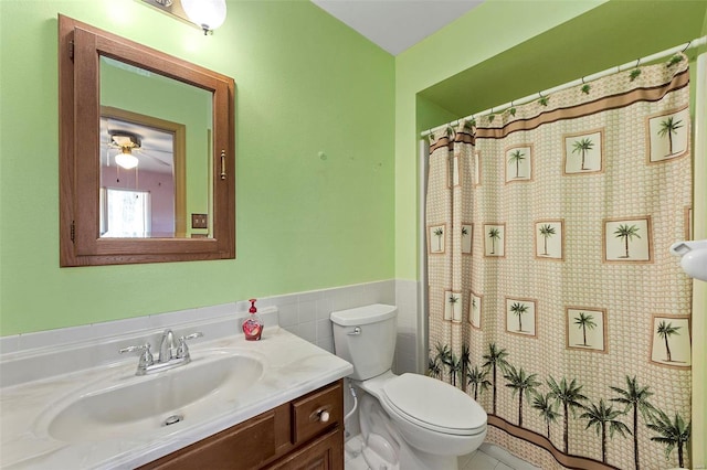 bathroom featuring vanity, a shower with curtain, a wainscoted wall, tile walls, and toilet