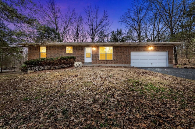 single story home featuring aphalt driveway, brick siding, and an attached garage