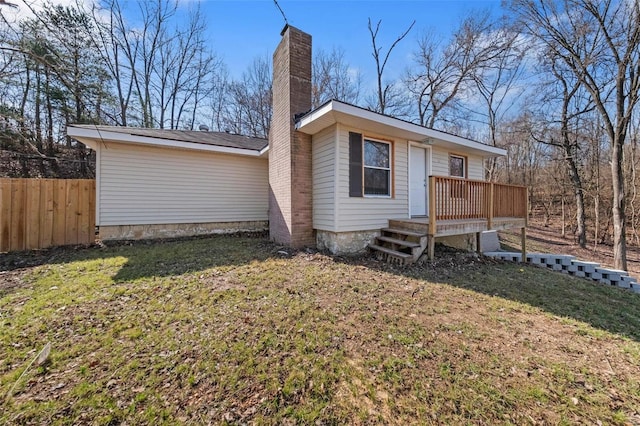 view of front facade featuring a front yard, a chimney, and fence