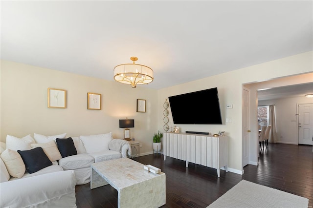 living room with dark wood finished floors, a notable chandelier, and baseboards