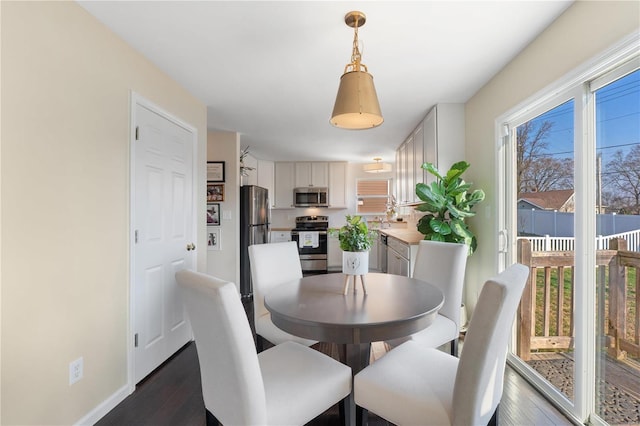 dining space with baseboards and dark wood-style flooring