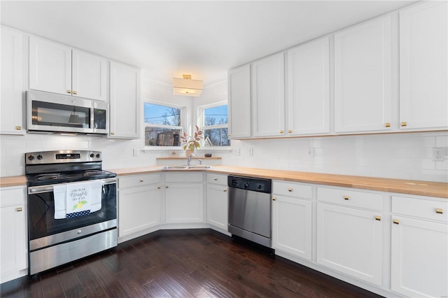 kitchen featuring butcher block countertops, a sink, backsplash, stainless steel appliances, and dark wood-style flooring