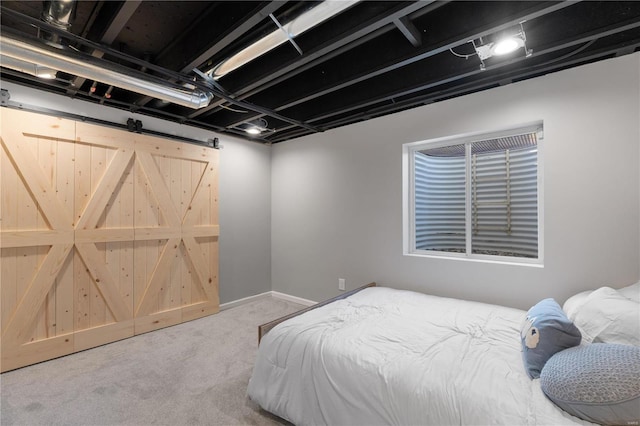 carpeted bedroom with a barn door and baseboards