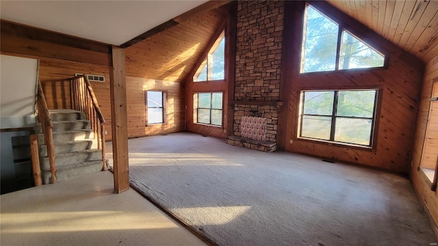 unfurnished living room with carpet, wood walls, and stairway