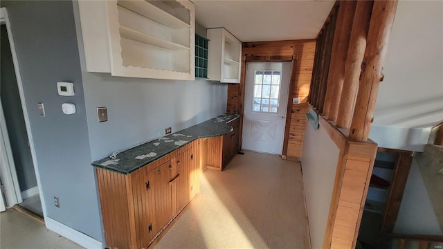 kitchen featuring dark countertops, wooden walls, light floors, and open shelves